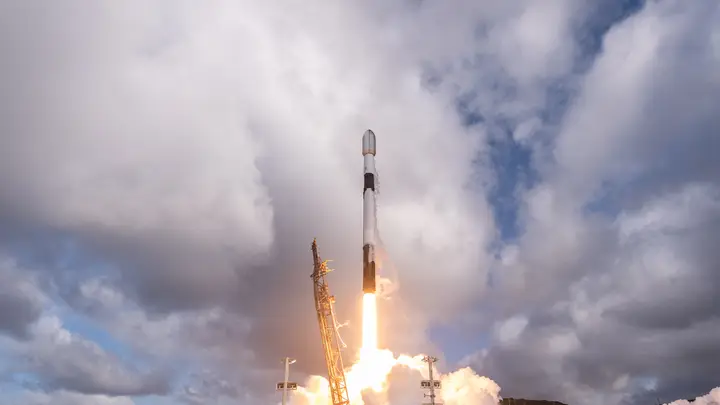 Falcon 9 lifting off from the pad with a plume of exhaust and steam