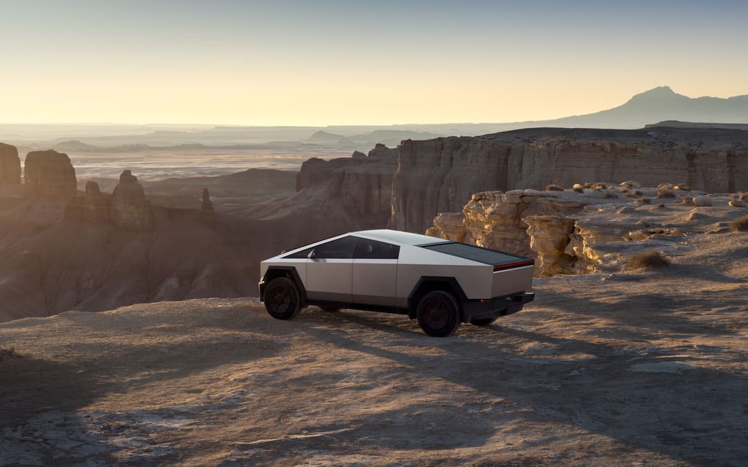 Stainless-steel Tesla Cybertruck on a desert road at dusk