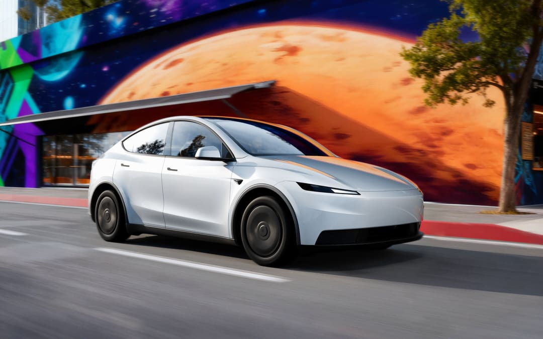 White Tesla Model Y driving past a colorful mural