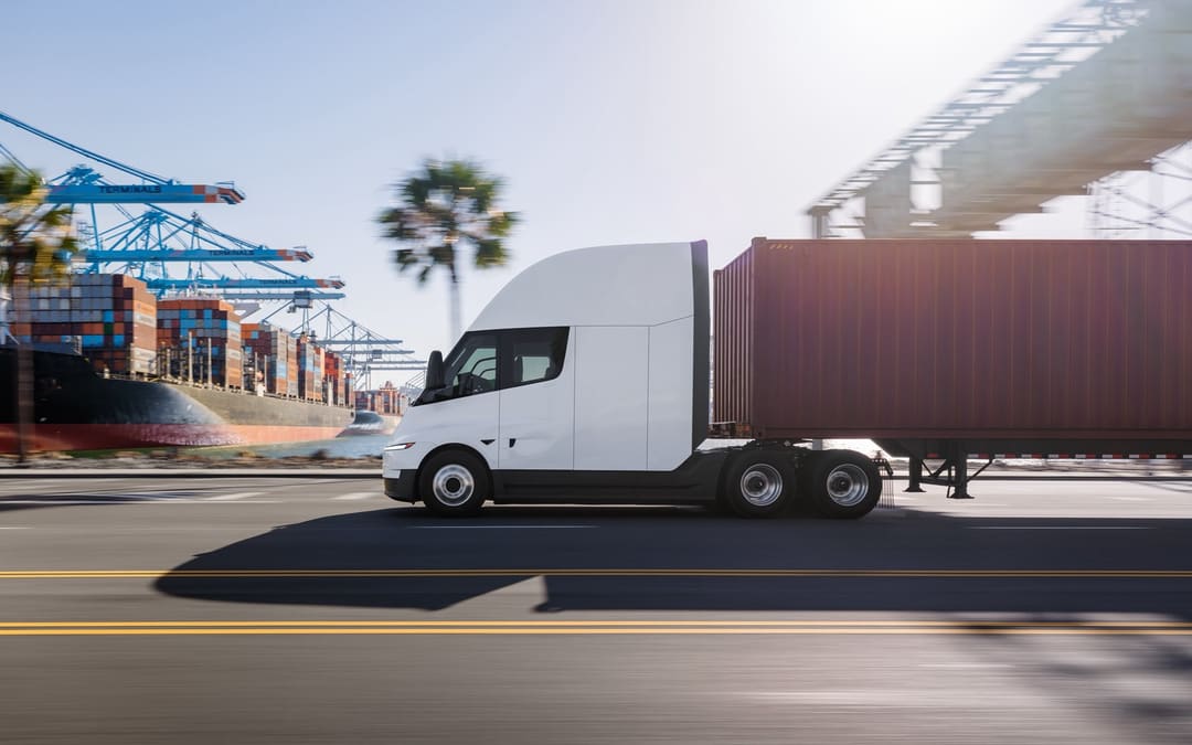 Tesla Semi pulling a red container trailer at a port