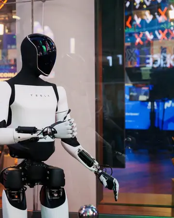 White and black Optimus standing at an indoor event, one hand raised