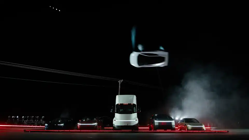 Tesla Roadster upside down in the air above a lineup of Tesla vehicles at night, thrusters firing, from Tesla's official kickflip video